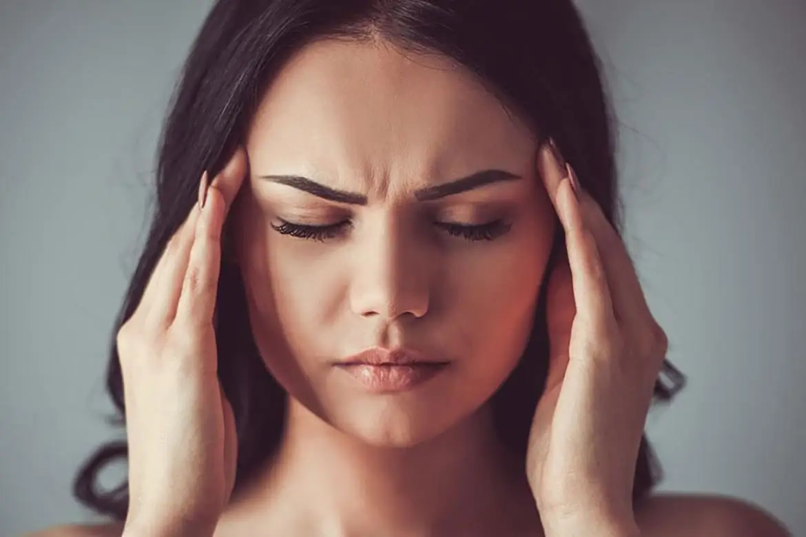 Woman holding her head in pain, depicting stress and headache symptoms